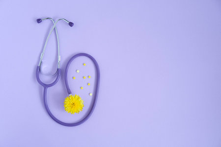 Stethoscope and yellow flower , yellow pills on lilac background with copy space. Medical flat lay. world pharmacist's dayの写真素材