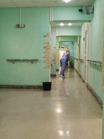 Woman in medical uniform is mopping floors in hospital corridor.の写真素材