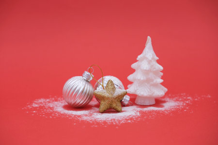 Silver Christmas balls, gold star and white Christmas tree on red background with copy space. Concept of winter card, sale of Christmas decorations.の写真素材