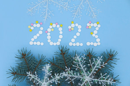 White medical pills in form of number 2023,christmas tree and snowflake on blue background close up. Christmas medical flatlay.の写真素材