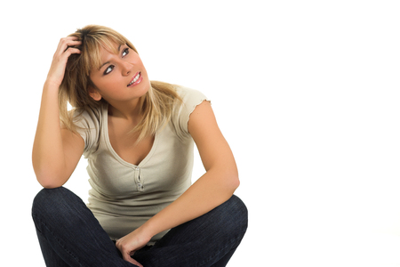 Young beautiful blond girl sitting and looking up isolated on white backgroundの写真素材