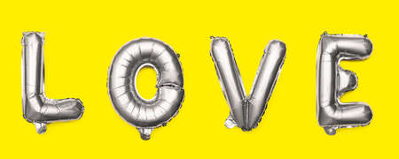 Love. Word made from silver balloons on a yellow background.の写真素材