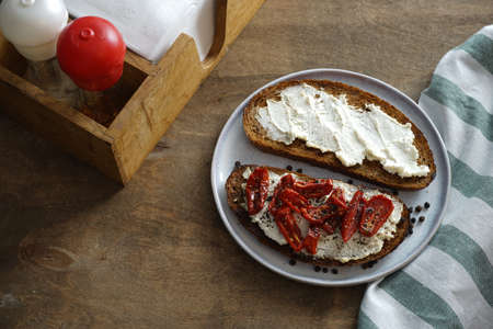 Homemade sandwich made of round homemade bread, dried tomatoes and cream cheese with spices....