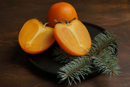 Two halves of ripe orange persimmon on a light flat plate.の写真素材
