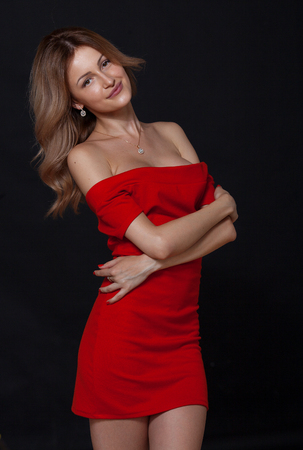 Fashion shot of a gorgeous young woman in elegant red dress. On black background.の写真素材