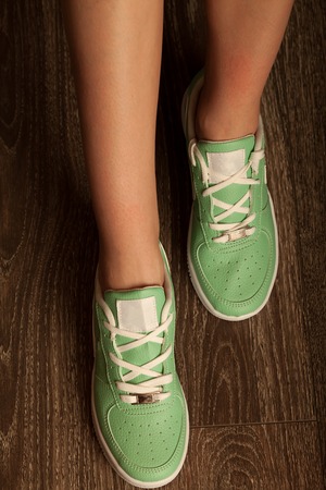Sexy woman leg in green Sneakers shoes walking on Dirty woodenの写真素材