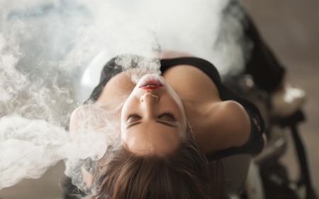 Young beautiful woman smoking ( vaping ) e-cigarette with smokeの写真素材