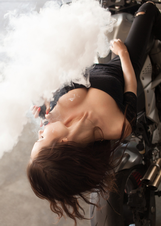 Young beautiful woman smoking ( vaping ) e-cigarette with smokeの写真素材