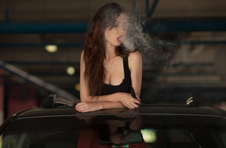 Young beautiful woman smoking ( vaping ) e-cigarette with smoke in car lukeの写真素材