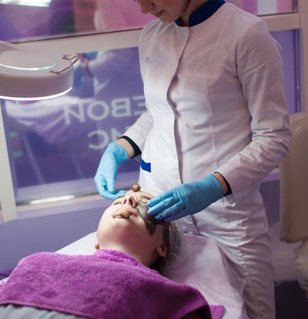 woman getting snail skin cleaning at beauty salon. Snail on face.の写真素材