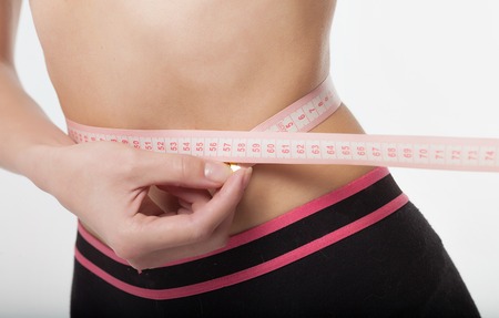 Woman measuring her slim body on white background. Health concept.