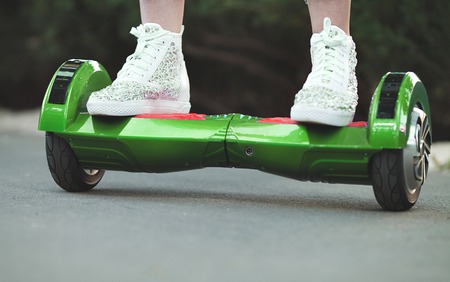 Feet of girl riding electric mini hover board scooter outdoors in park. Ecological city transportation on battery power.の写真素材