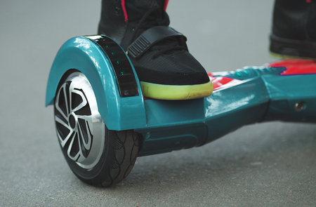 Feet of girl riding electric mini hover board scooter outdoors in park. Ecological city...