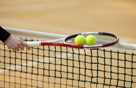 tennis racket with ball on clay court