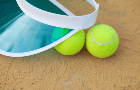 Clay tennis court with tennis ball, netting, cap.の写真素材