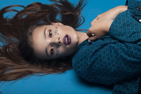 Woman with writing fuck you on her face. Creative make up