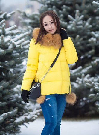 Portrait of young woman near fir-tree in winter. Female portrait. Woman in yellow winter coat.の写真素材