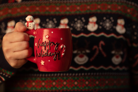 Merry Christmas and Happy New Year greeting card. Woman's hand holding red mug with lettering.の写真素材
