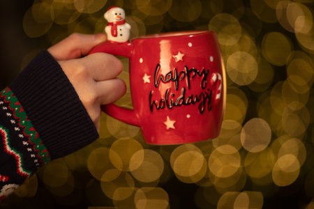Merry Christmas and Happy New Year! Woman holding a cup of hot drink on bokeh background.の写真素材