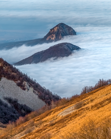 Mountains in the fog, haze. The Main Caucasian Range. Multicolored background. Mountains at sunset. Winter fog.の写真素材