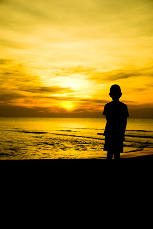 lonely boy on the beach Silhouetteの写真素材