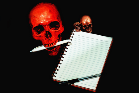 Skull note taking still life black backgroundの写真素材