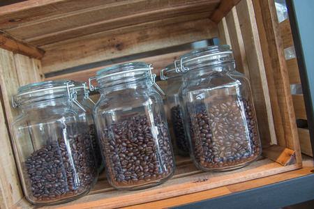 Coffee beans into a glass pot beside other one with natural roasted coffee beansの写真素材