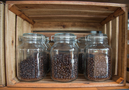 Coffee beans into a glass pot beside other one with natural roasted coffee beansの写真素材