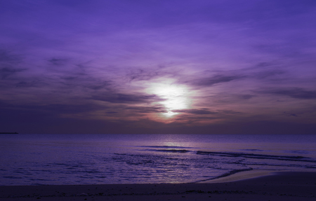Sun sets over horizon of ocean. Sky, water and shore in the evening paint, purple skyの写真素材