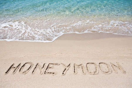 Honeymoon written on the sandの写真素材