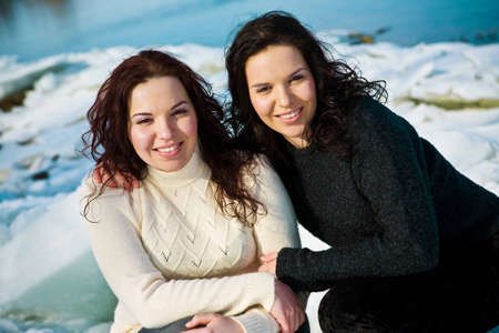 Girls twins near river in winterの写真素材