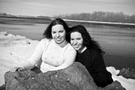 Girls twins near river in winterの写真素材