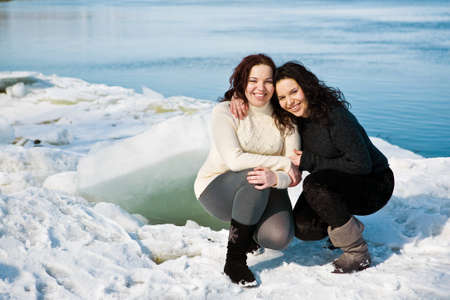 Girls twins near river in winterの写真素材