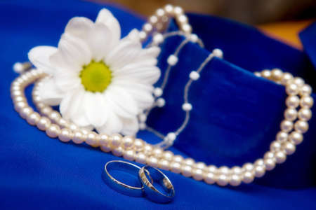 Wedding rings and flower on a blue dressの写真素材