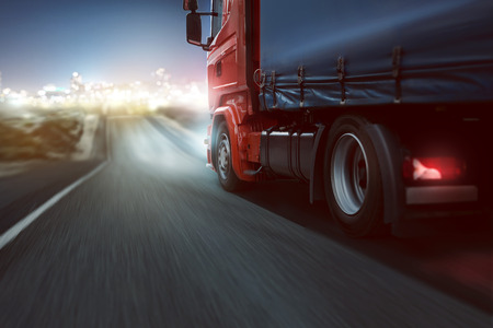 Truck drives on a country road with bokeh lights in the distanceの写真素材