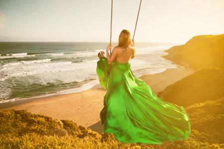 Woman on a swing above the beachの写真素材