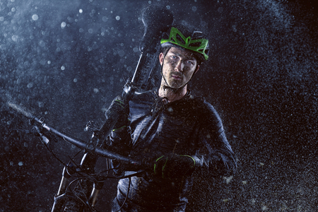 Mountainbiker carries his bike through the rainの写真素材