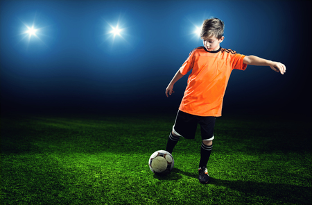 Little boy is playing soccer in a stadiumの写真素材