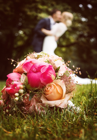 Bride and groom kissing behind bouquet of flowersの写真素材