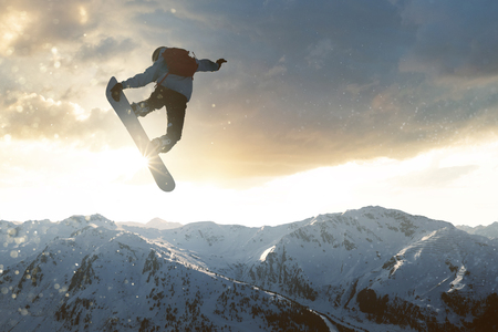 Snowboarder jumping in front of mountainsの写真素材