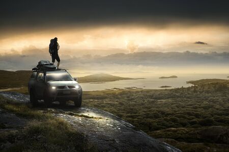 Man stands on all-terrain vehice on the coastの写真素材