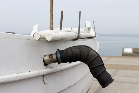 A boat laying ashore with the oars and the exhaust pipe
