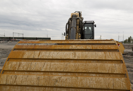 A bucket on an excavator with some wagons in the backgroundの写真素材