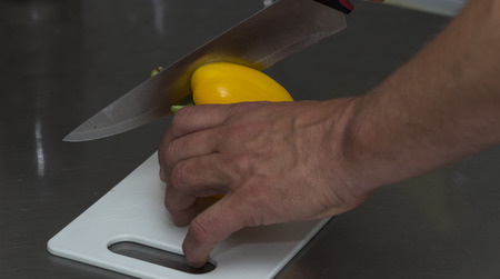 A male hand cutting peppers on a cutting boardの写真素材