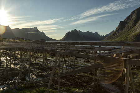 A traditional stock fish drying equipment in Norway in front of a mountain and a big flareの写真素材