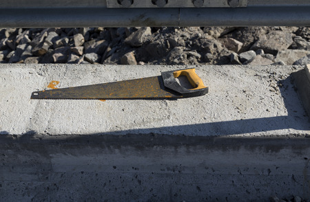 An old rusty saw laying on a concrete piece of a bridgeの写真素材