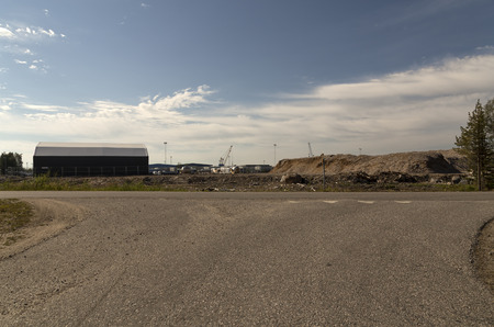 An industrial area with some light poles and a crane in the background. A tent for storage in the foregroundの写真素材