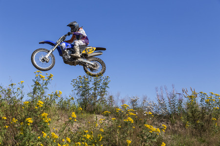 A motorcyclist in full speed from below with some flowers in the foregroundのeditorial素材