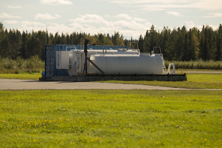 Fuel tanks on an air field with some grass in the foreground and forest in the backgroundの写真素材