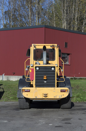 The rear of a parked tractor with some trees in the background